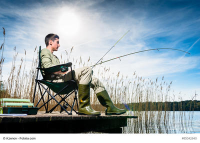 Bild vergrern: Man fishing at lake sitting on jetty close to the water